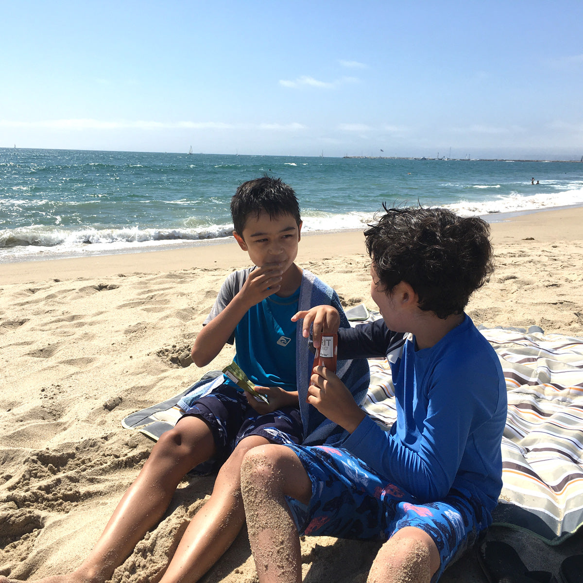 Two kids eating SPIRIT Almond at the beach